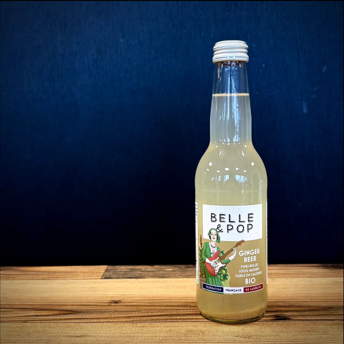 Belle & Pop Ginger Beer BIO aux fines bulles, bouteille élégante posée sur table en bois, ambiance apéritif chaleureuse et artisanale.