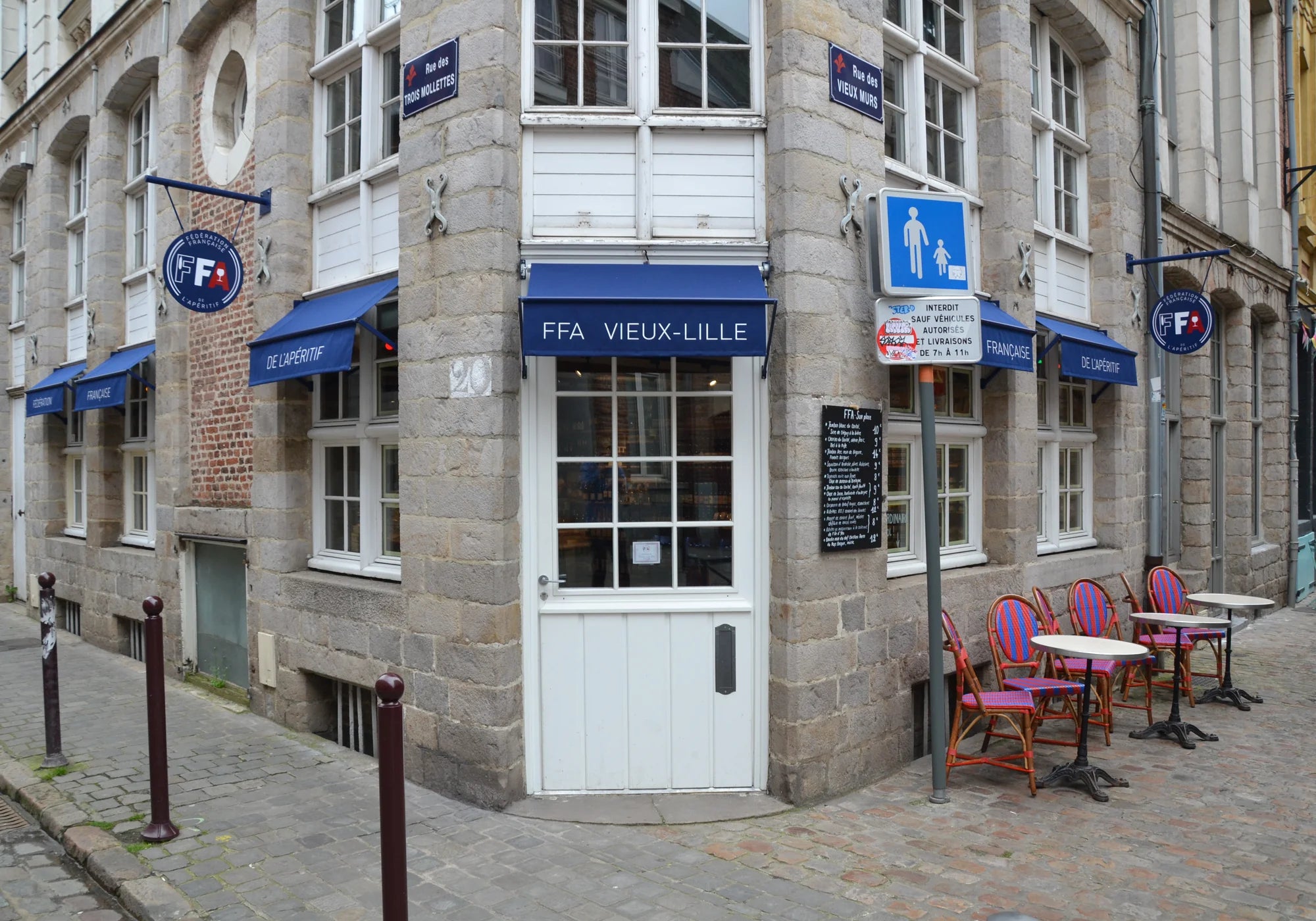 Façade d’angle de la boutique FFA Vieux-Lille avec enseignes bleues et terrasse extérieure — ambiance chaleureuse et authentique de l’apéritif à la française.