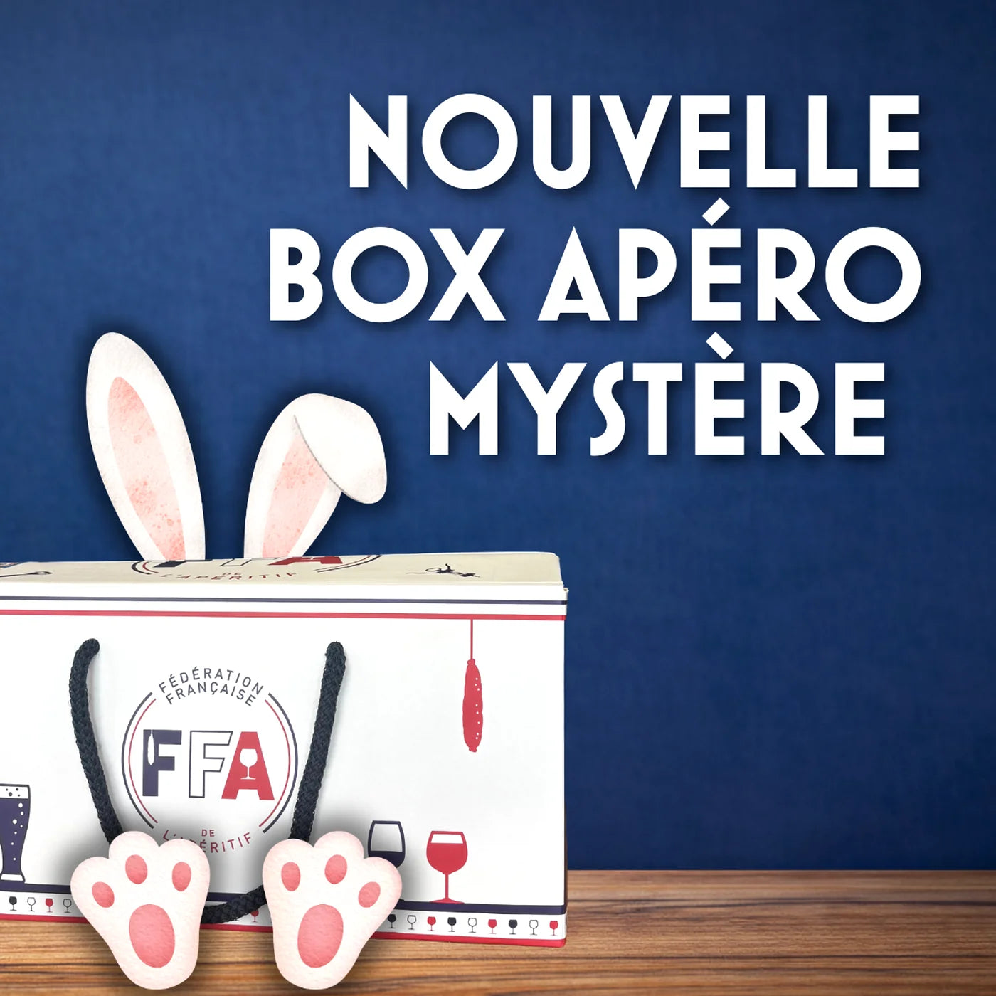 Box Apéro Mystère de la Fédération Française de l’Apéritif posée sur une table en bois avec des oreilles de lapin — visuel gourmand et convivial pour une surprise apéritive.