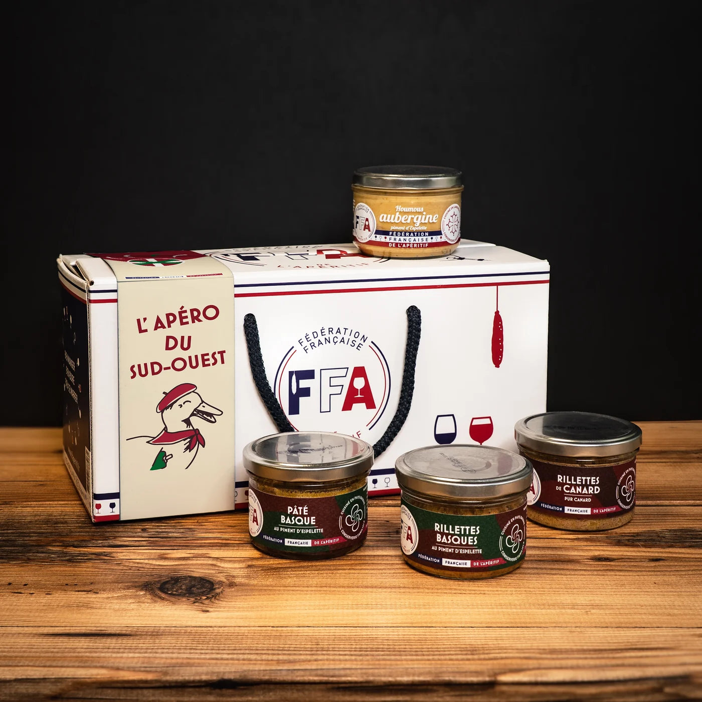 Coffret apéritif du Sud-Ouest de la Fédération Française de l’Apéritif — rillettes de canard, pâté basque, houmous d’aubergine et rillettes basques dans un coffret FFA illustré, ambiance conviviale et gourmande du Sud-Ouest.