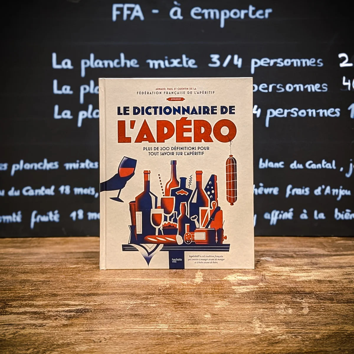 Le Dictionnaire de l’Apéro FFA – livre illustré sur l’art de l’apéritif à la française, posé sur une table en bois.