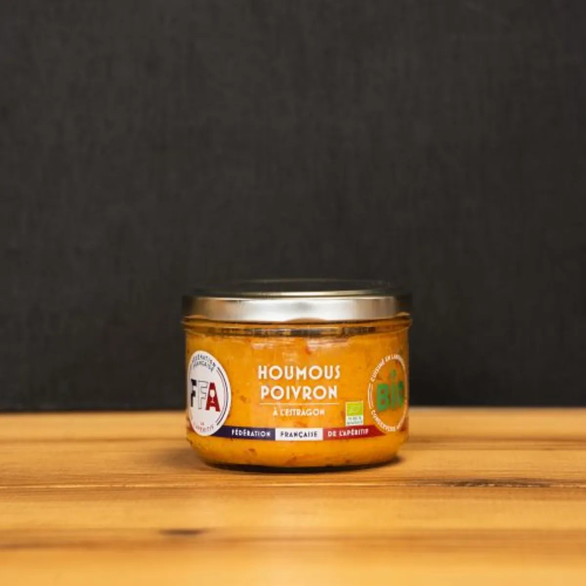 Houmous poivron à l’estragon bio FFA, pot artisanal du Languedoc sur planche en bois, apéritif gourmand et ensoleillé.