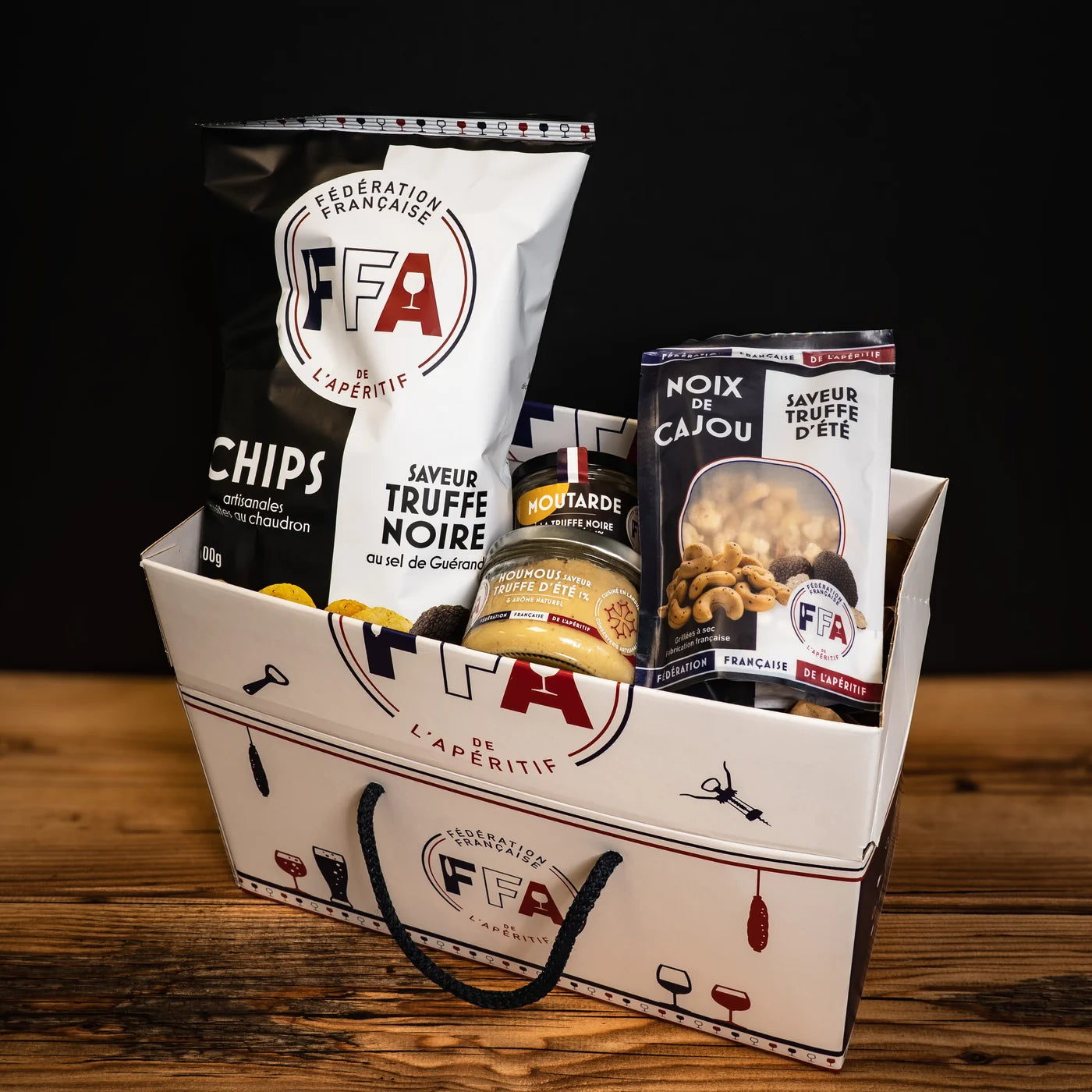 Panier cadeau FFA rempli de produits apéritifs à la truffe — chips, noix de cajou, houmous et moutarde artisanale.