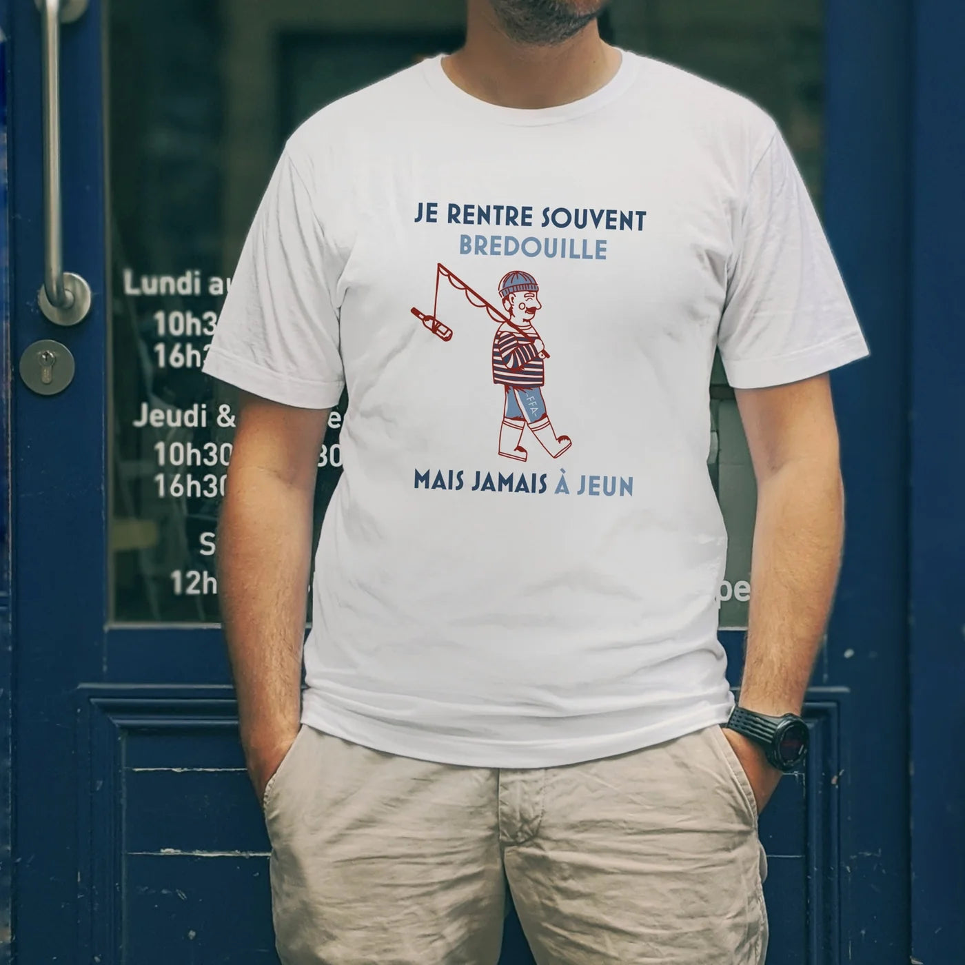 T-shirt blanc FFA “Je rentre souvent bredouille mais jamais à jeun” porté devant une devanture bleue — illustration pêcheur humoristique version apéro.