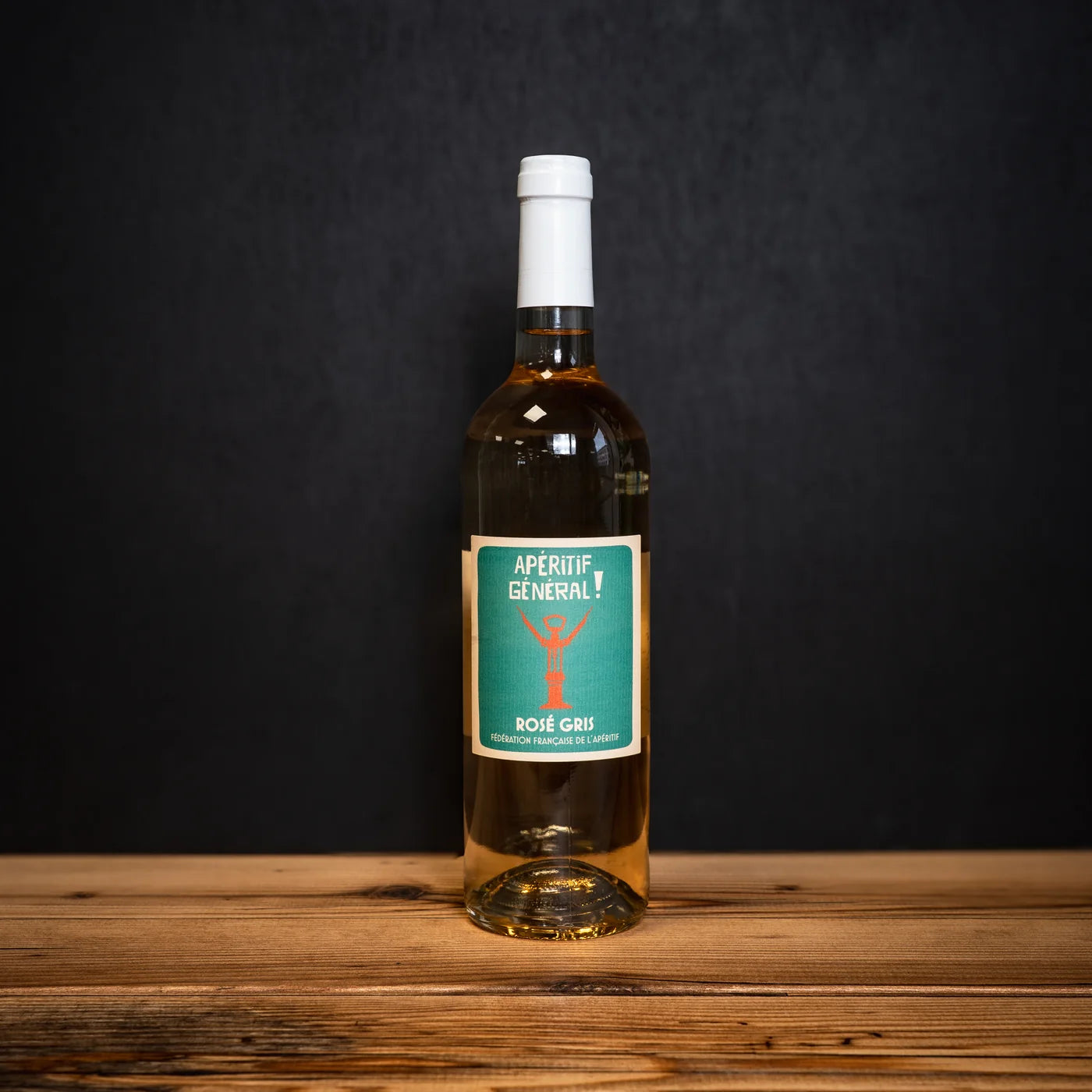 Bouteille de vin rosé gris Apéritif Général FFA posée sur une table en bois, étiquette turquoise sur fond sombre.