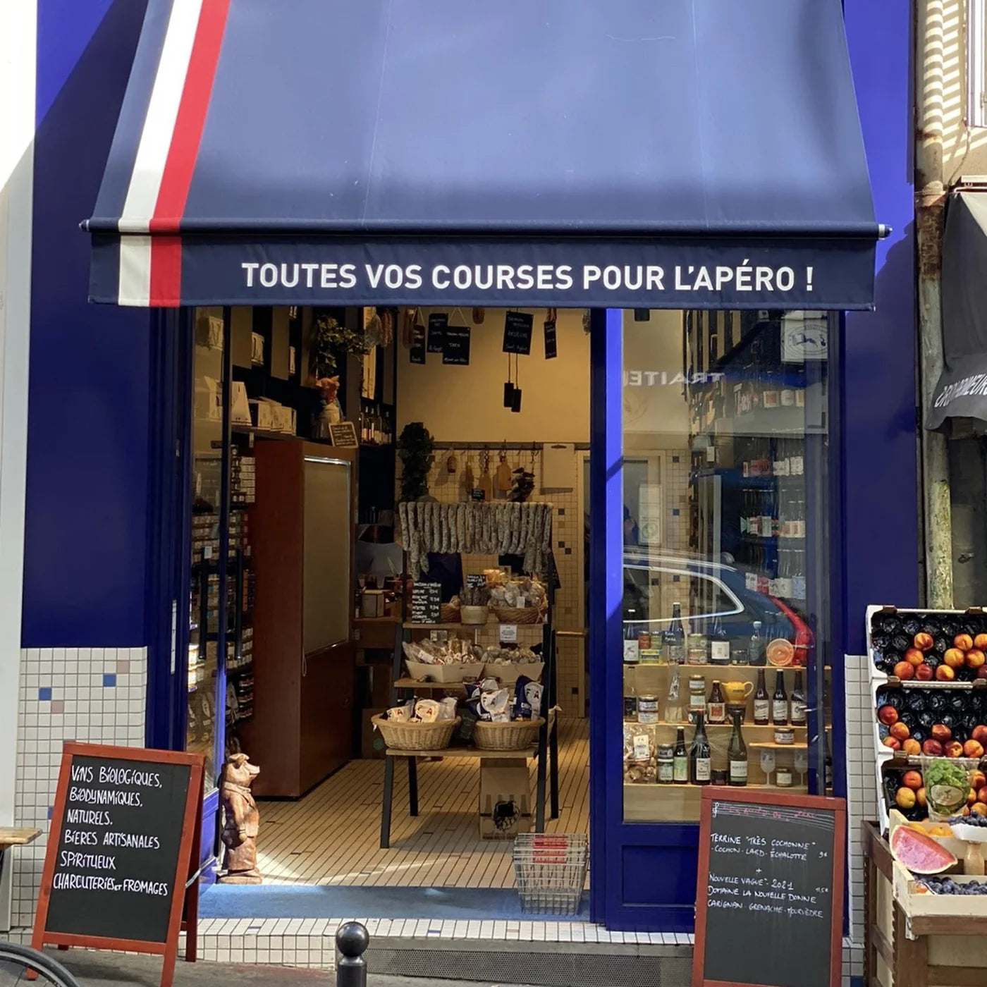 Devanture bleue de la boutique Fédération Française de l’Apéritif à Paris avec auvent tricolore et produits artisanaux visibles à l’intérieur.