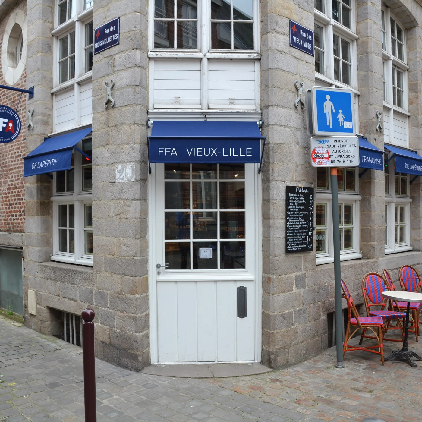 Façade en pierre de la boutique FFA Vieux-Lille avec auvent bleu, terrasse et enseigne Fédération Française de l’Apéritif — ambiance conviviale et authentique.