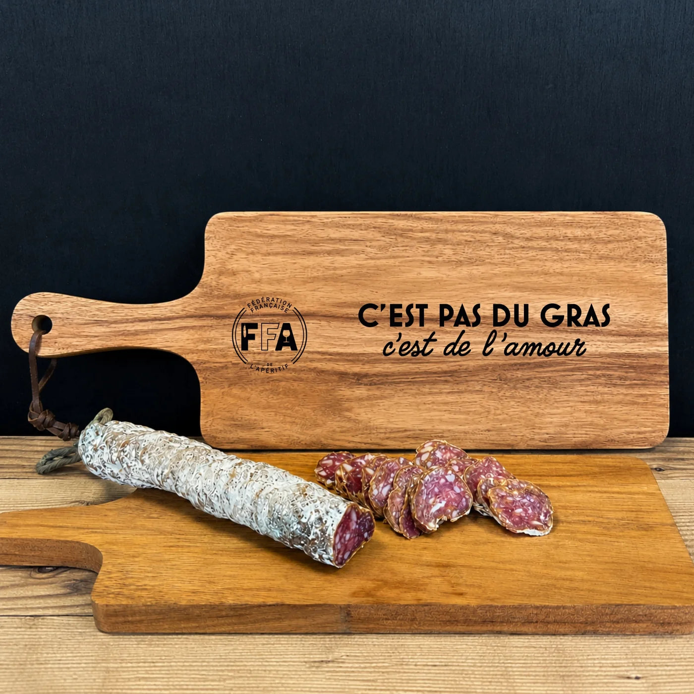 Planche en bois FFA gravée “C’est pas du gras c’est de l’amour” présentée avec un saucisson sec pour l’apéritif. 