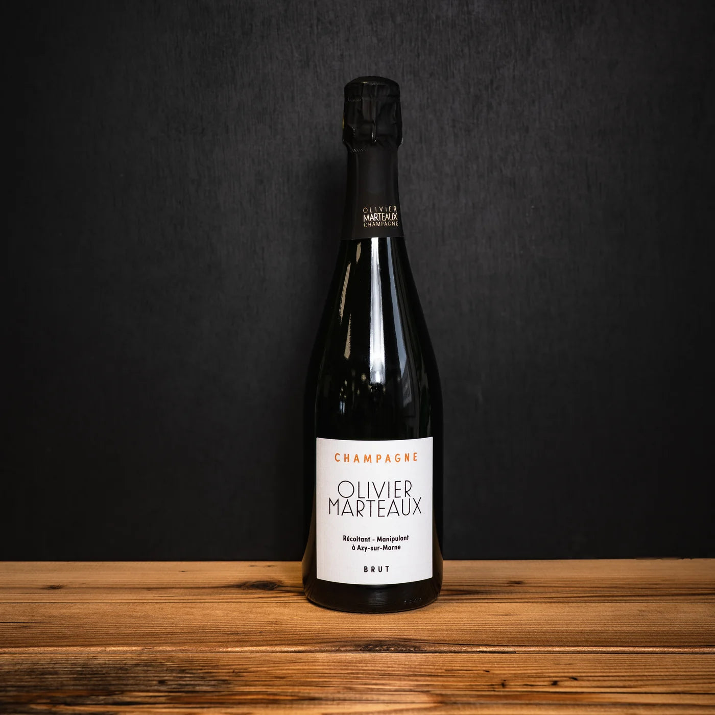 Bouteille de Champagne Olivier Marteaux Brut posée sur une table en bois — ambiance élégante et conviviale, parfaite pour l’apéritif.
