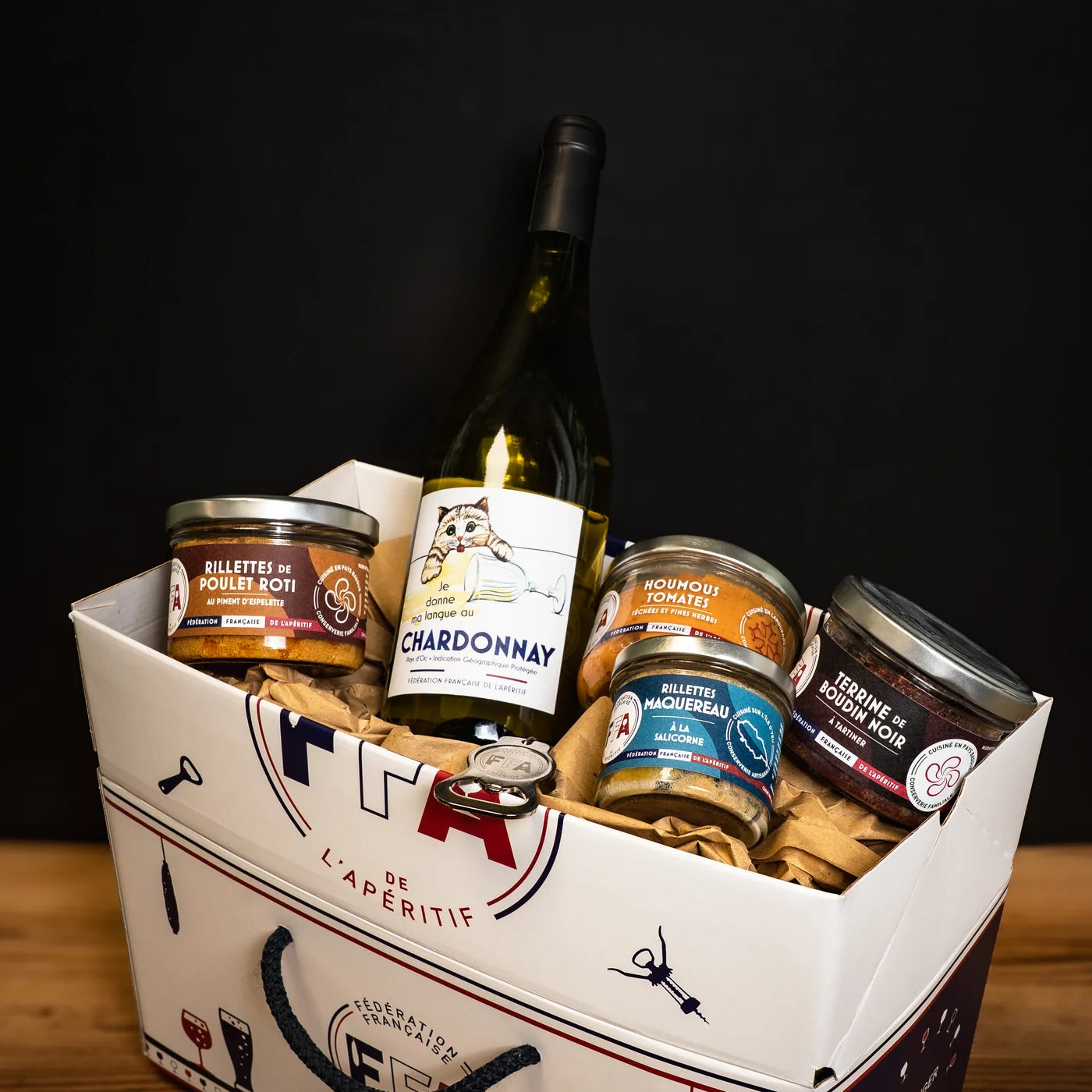 Coffret apéritif gourmand de la Fédération Française de l’Apéritif avec une bouteille de Chardonnay, rillettes de poulet rôti, houmous aux tomates, rillettes de maquereau et terrine de boudin noir — apéro artisanal et festif.