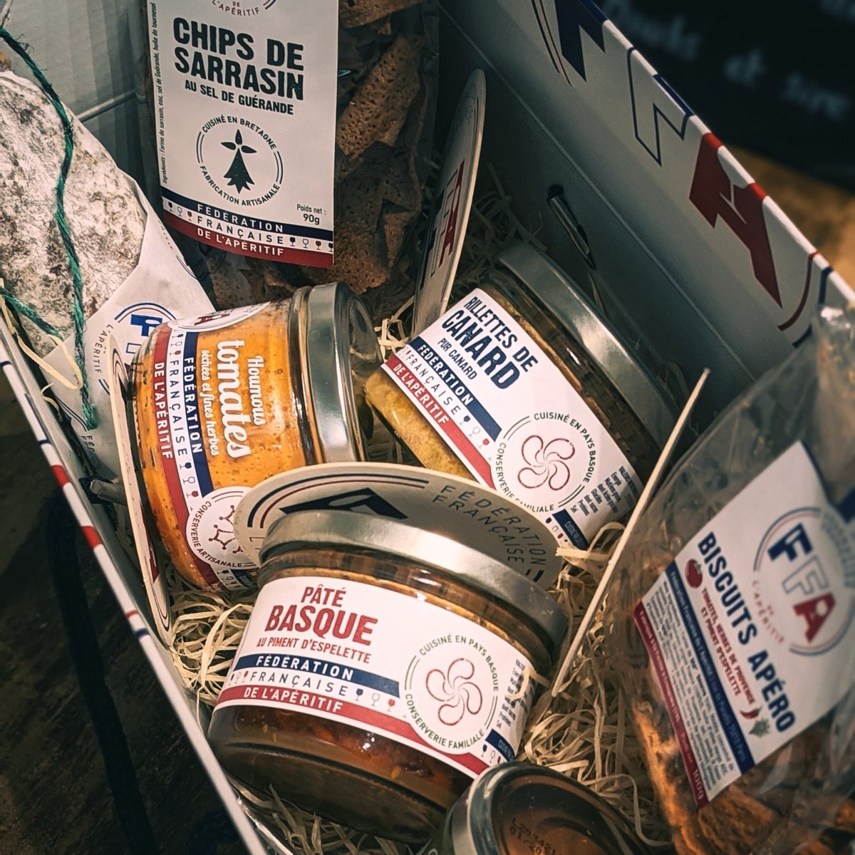 Gros plan sur le coffret apéritif FFA contenant pâté basque, rillettes de canard, chips de sarrasin et biscuits apéro.