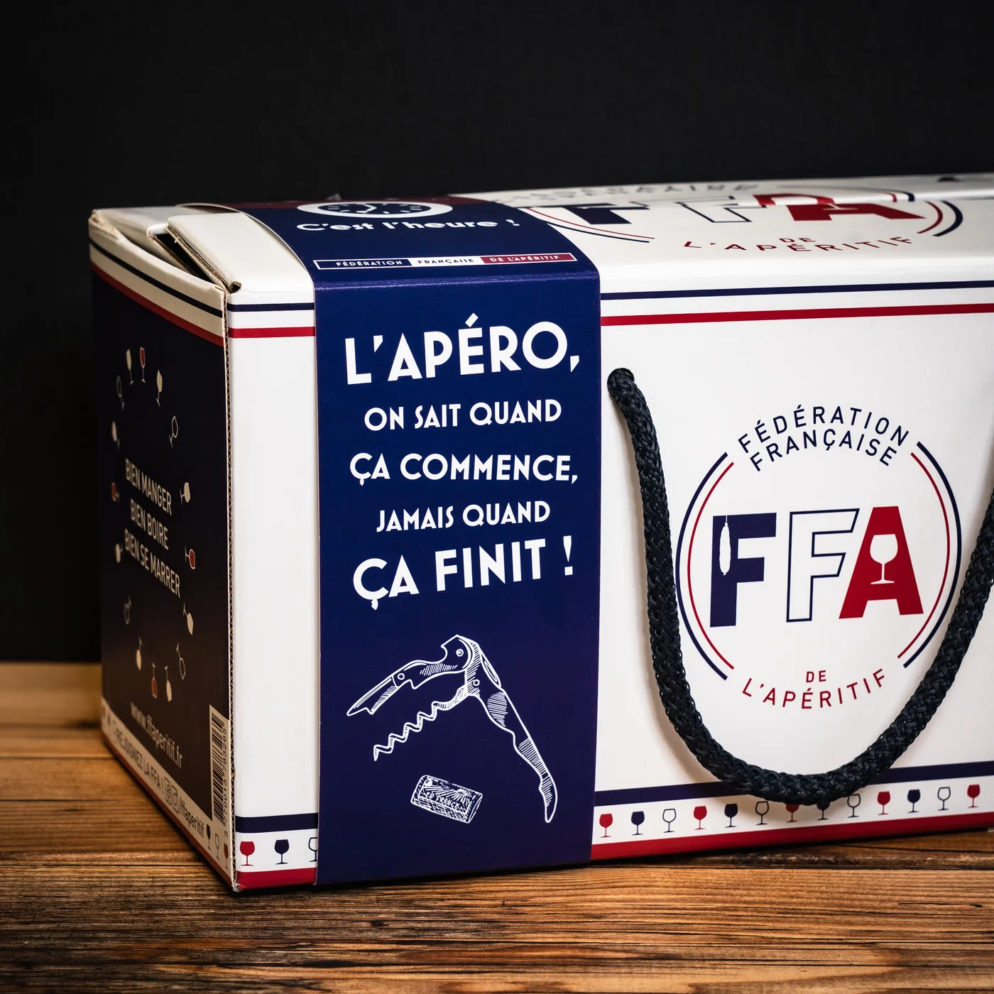 Coffret cadeau de la Fédération Française de l’Apéritif au design bleu marine avec l’inscription humoristique « L’apéro, on sait quand ça commence, jamais quand ça finit ! » — ambiance festive et conviviale.