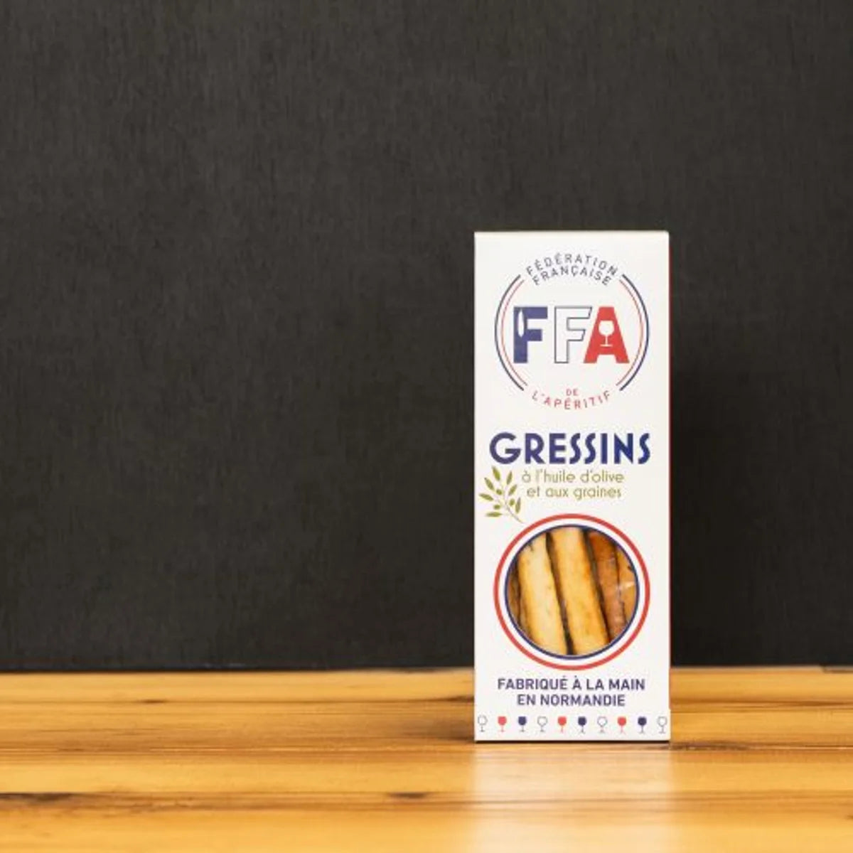 Gressins artisanaux FFA à l’huile d’olive et aux graines, fabriqués à la main en Normandie et présentés sur planche en bois pour l’apéritif.