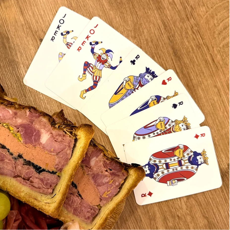 Partie de cartes FFA en cours autour d’une planche apéritive avec fromage, jambon et verres de vin et bière