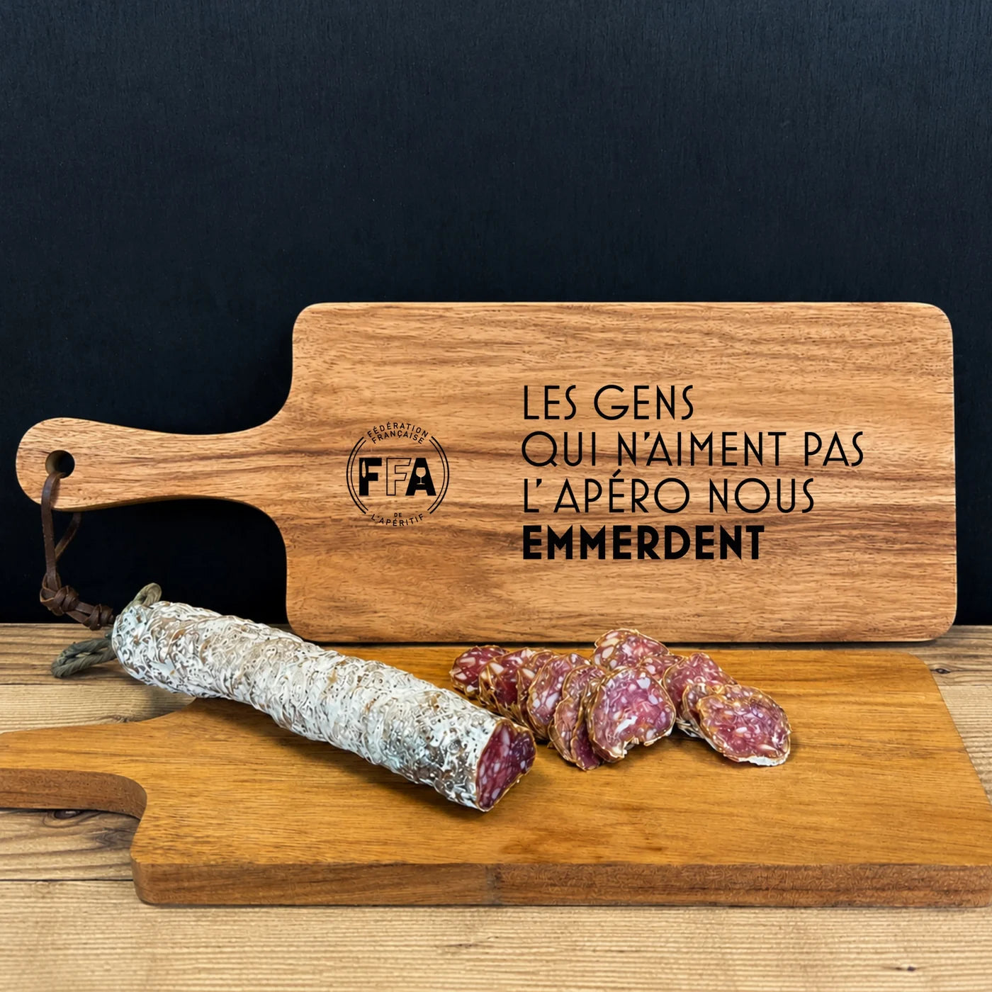 Grande planche à découper FFA gravée d’une citation humoristique sur l’apéro accompagnée d’un saucisson artisanal.