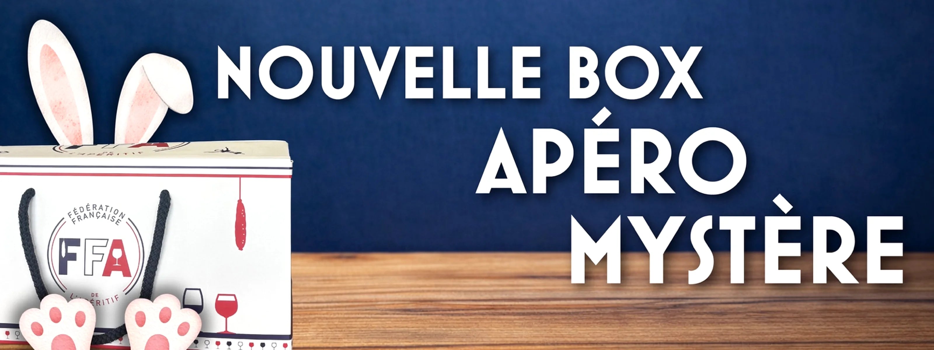 Nouvelle Box Apéro Mystère de la Fédération Française de l’Apéritif posée sur une table en bois avec des oreilles de lapin — visuel promotionnel gourmand pour découvrir une box apéritive surprise.