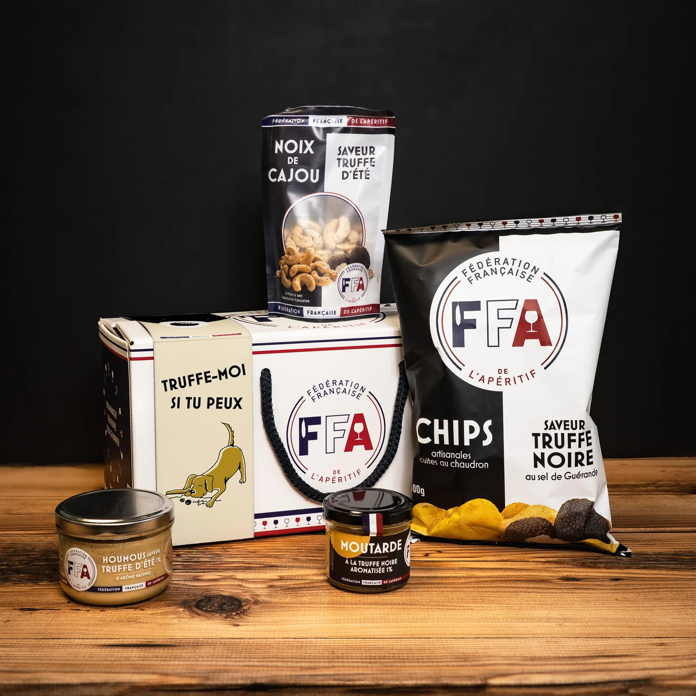Ensemble de produits apéritifs FFA saveur truffe présenté avec la boîte cadeau — chips, noix de cajou, moutarde et houmous à la truffe.
