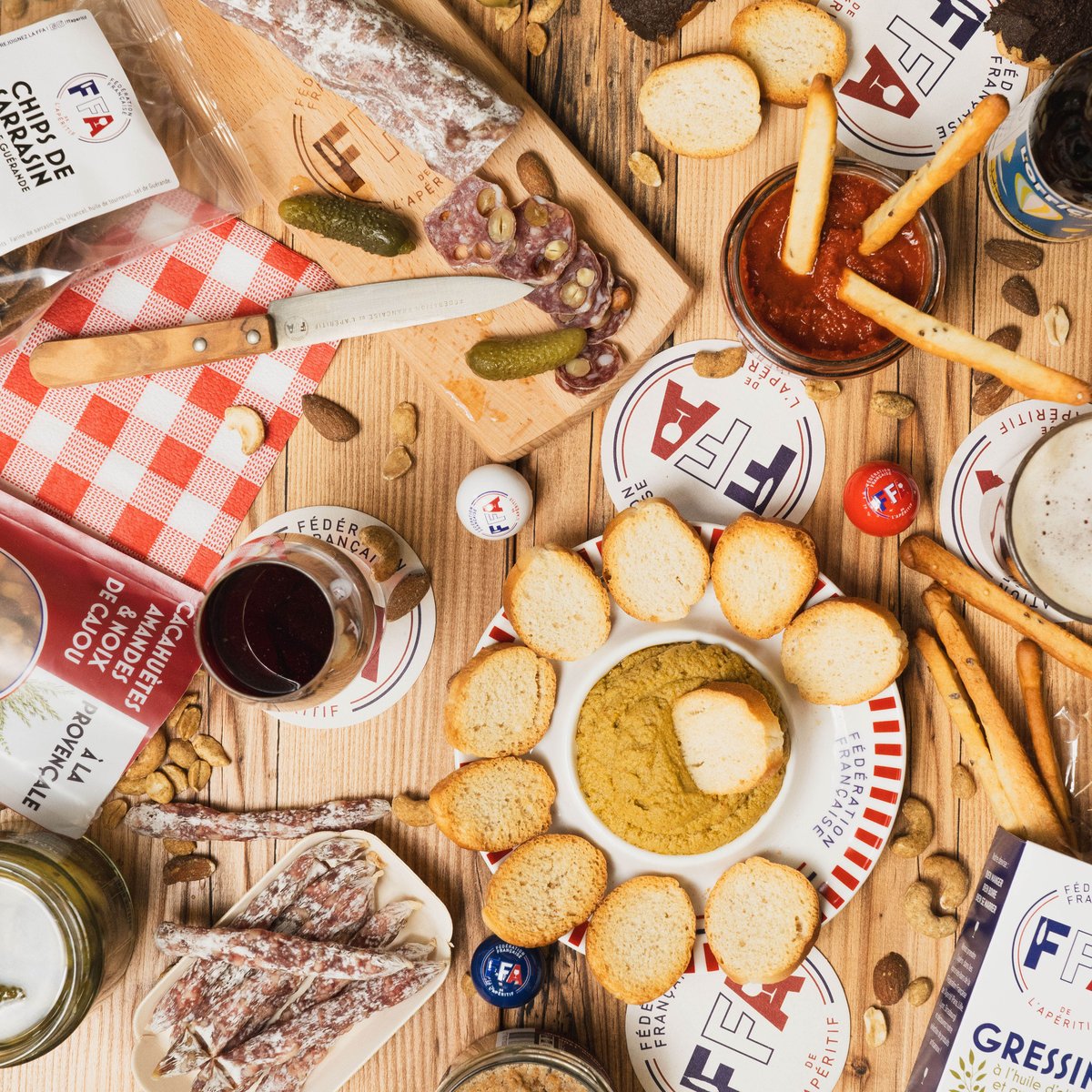 Plateau apéritif FFA avec saucisson, tartinables, chips, toasts et gressins sur table en bois, ambiance conviviale.