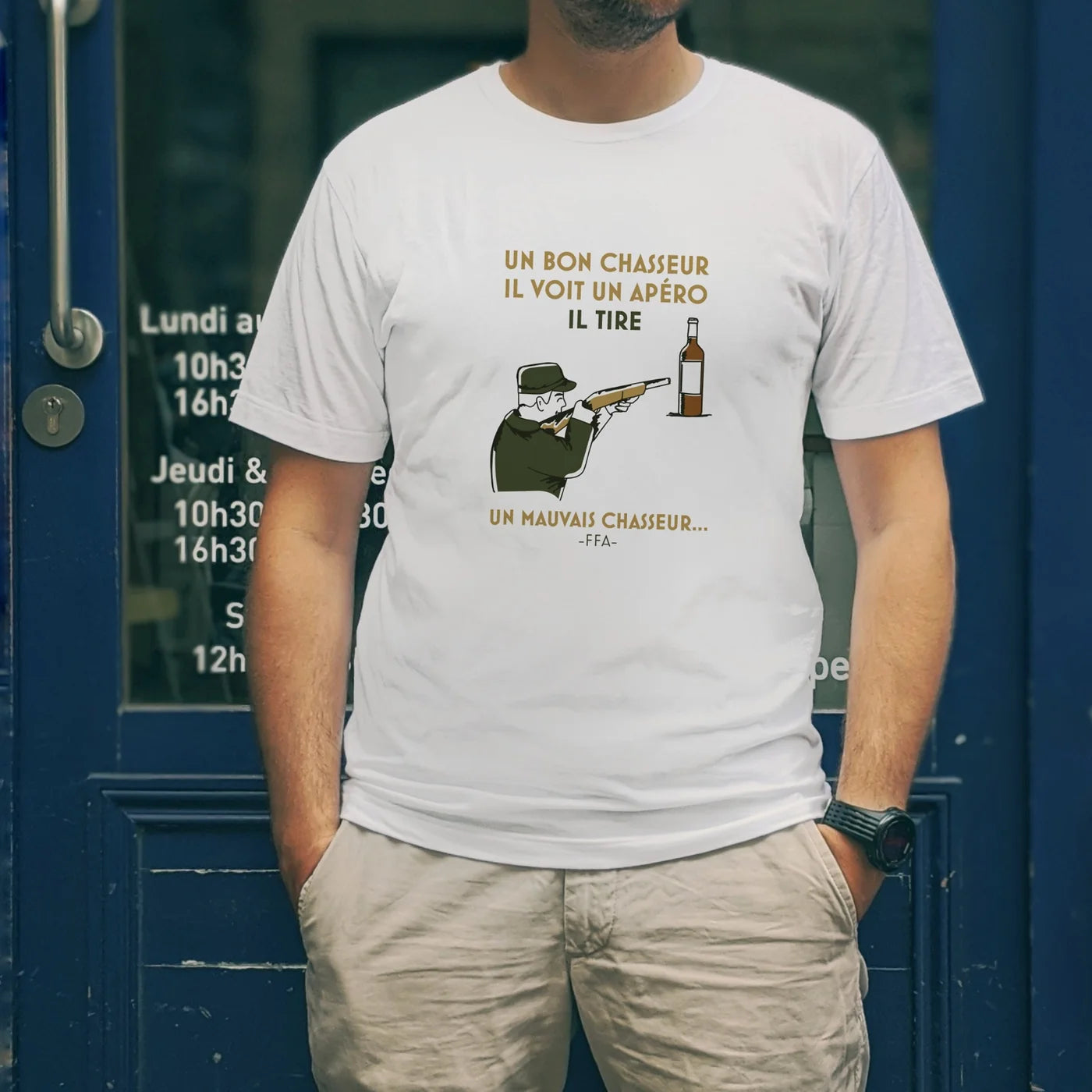 T-shirt FFA “Un bon chasseur il voit un apéro il tire — un mauvais chasseur…” porté devant une devanture bleue, illustration humour apéritif.